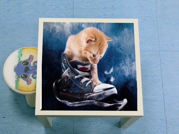 Table Cute kitten plays in sneakers